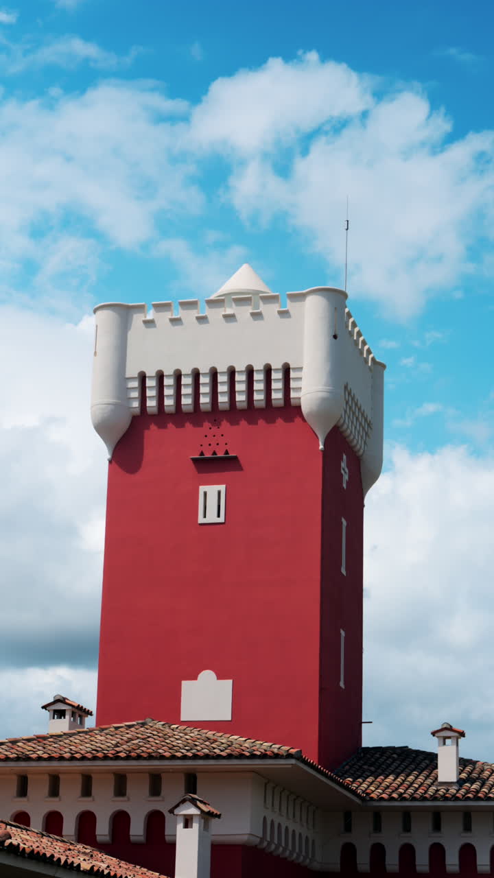 View of the red tower of the Cremat Castle Winery over blue sky. Vertical
