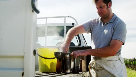 beekeeper preparing bee smoker on truck