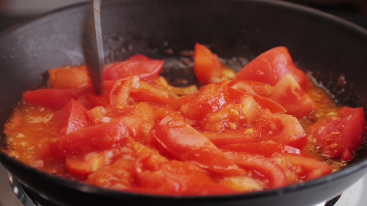Cooking fresh peeled sliced tomato Juice sauce in pan, peeled tomatoes boiling in their own juice, making tomatoes pasta sauce .Top view close up, Italian traditional cuisine food.