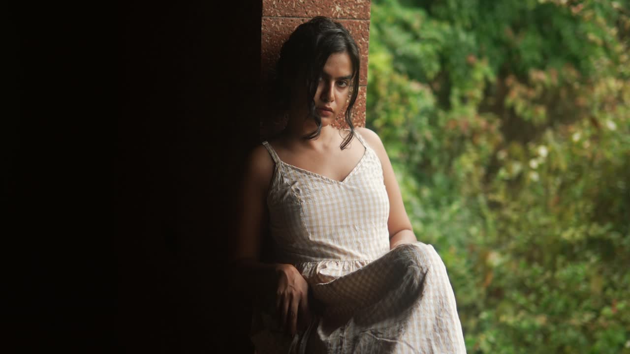 잔잔한 초록색을 내려다보는 창문 에 사려 깊게 앉아있는 젊은 여성, 자연빛이 그녀의 얼굴을 비추고