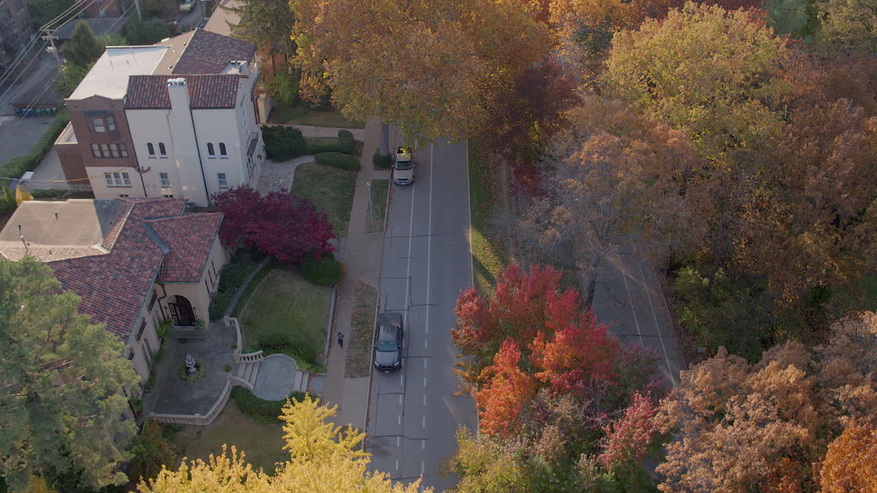 vista aérea del bulevar wydown mientras los autos conducen por la calle y la cámara retrocede sobre hermosos árboles de otoño