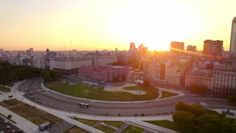 Dolly-in-aerial-view-of-the-Casa-Rosada,-the-government-house-of-the-Argentine-nation-with-the-sun-in-the-background-leaving-a-few-rays-of-light,-epic-shot