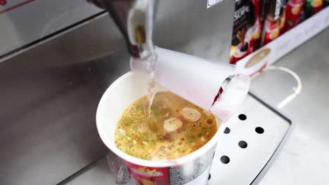 agua caliente que se vierte en la taza de fideos instantáneos