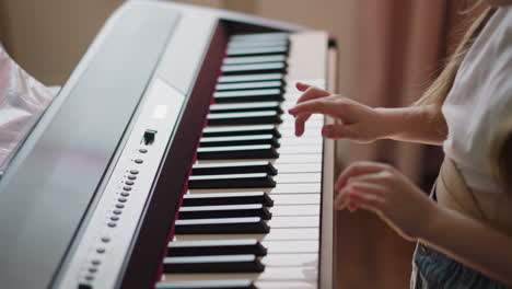 Student-plays-melody-on-electrical-piano-in-living-room