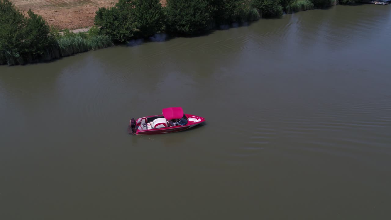 Man Stand Put on Monoski on Red Ski Boat in Dirty River DISTANT AERIAL