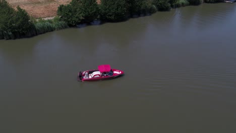 man stand put on monoski on red ski boat in dirty river distant aerial