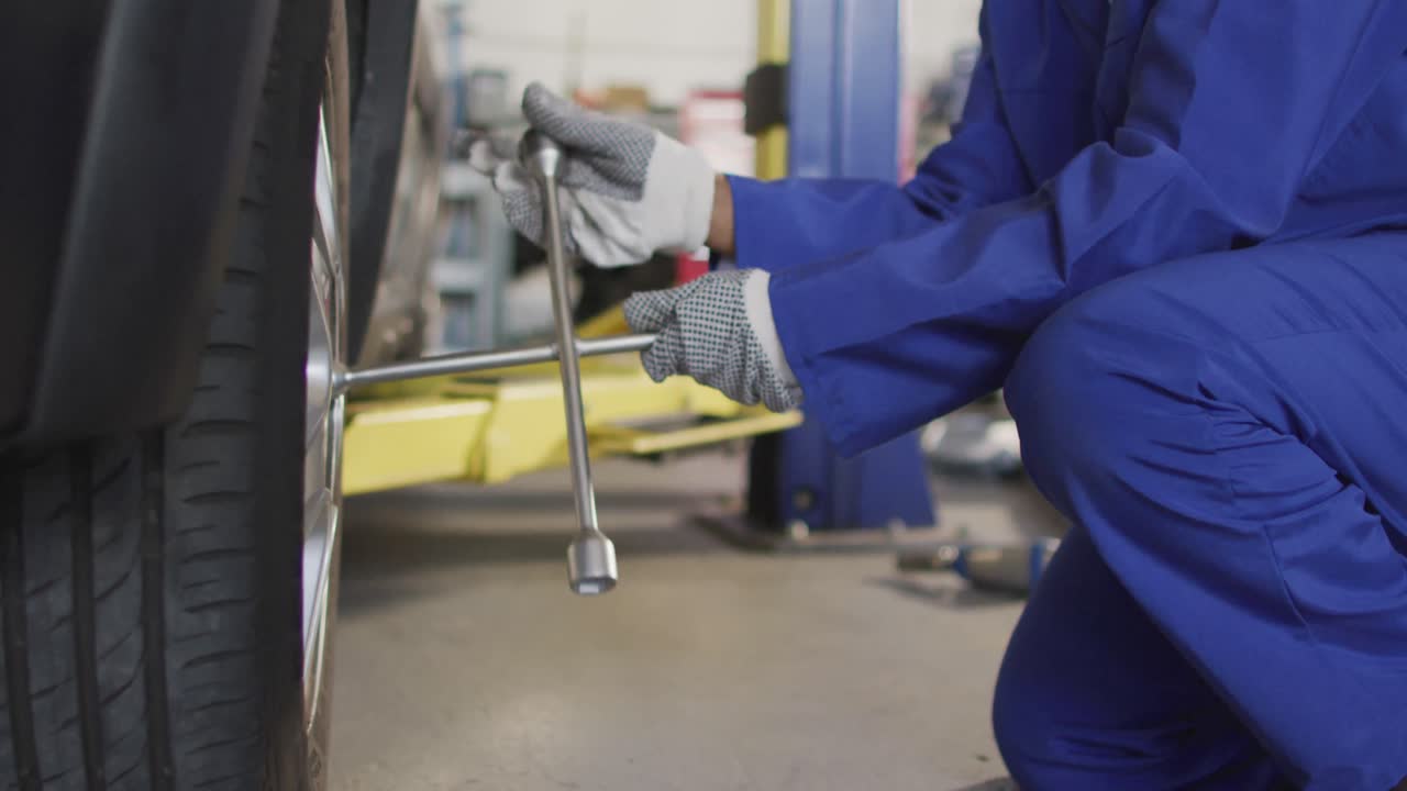 video de la sección media de una mecánica de automóviles afroamericana cambiando un neumático