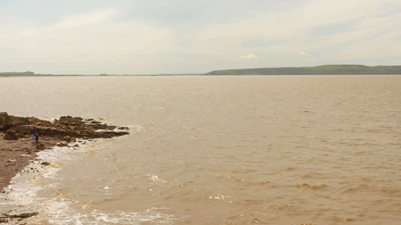 Brown Sea Water Lapping On Rocky Shore At Knightstone Island In Weston-Super-Mare, Somerset, England. wide shot