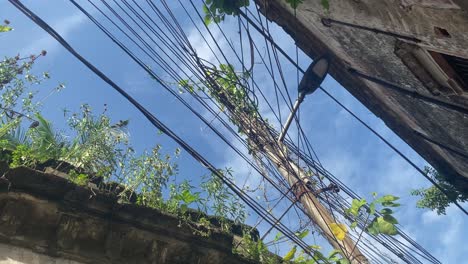 overhead mess of open electrical wires with old building of developing country