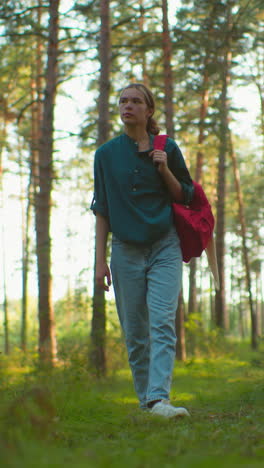 mujer excursionista caminando a través de un bosque sereno, llevando una bolsa roja sobre el hombro, pareciendo cansada pero decidida, la luz del sol se filtra suavemente a través de los árboles altos, arrojando un brillo cálido
