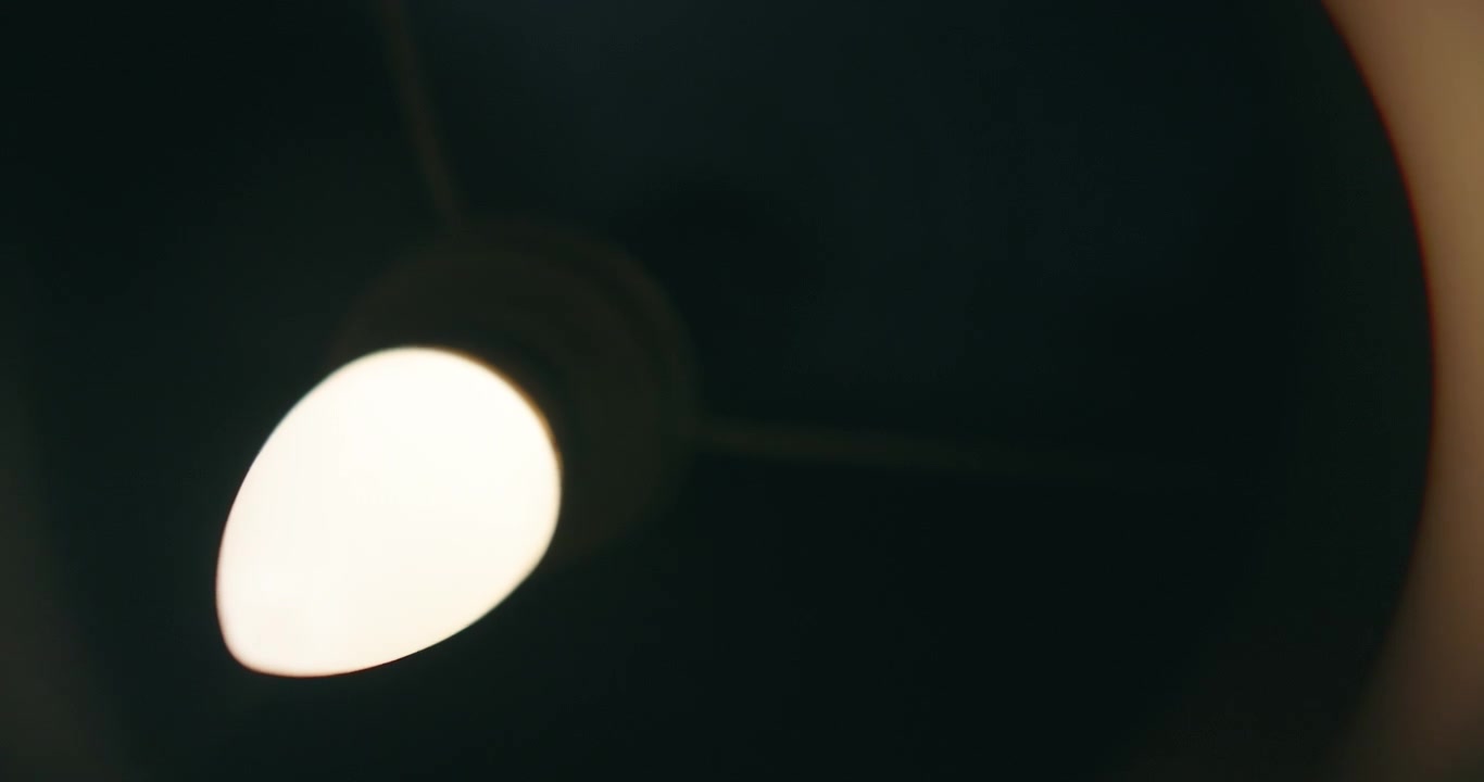 Close-up of a light bulb turning on in a dark room, feeling of warmth