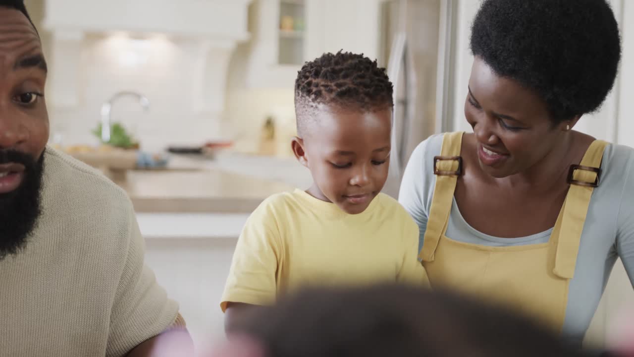 Coppia afroamericana felice con il figlio che si gode il pasto nella sala da pranzo, al rallentatore.
