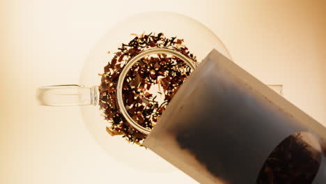 loose leaf tea pouring into a glass teapot