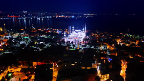 distancing from a beautiful luminous mosque in the panorama of istanbul. drone footage over the night city with street lights on