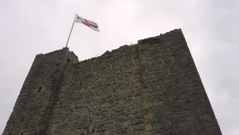 st george cross flag waving on top of gothic castle turret tilt shot