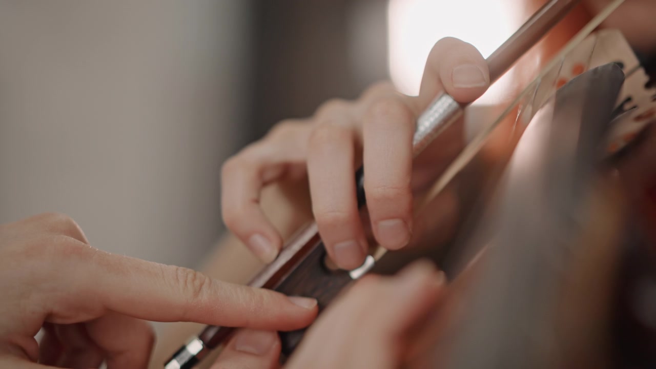 Redhead caucasian violinist handson lesson with coach, closeup of hands and finger placement on fingerboard, teacher adjusting posture, bow pressure guidance, warm classroom atmosphere