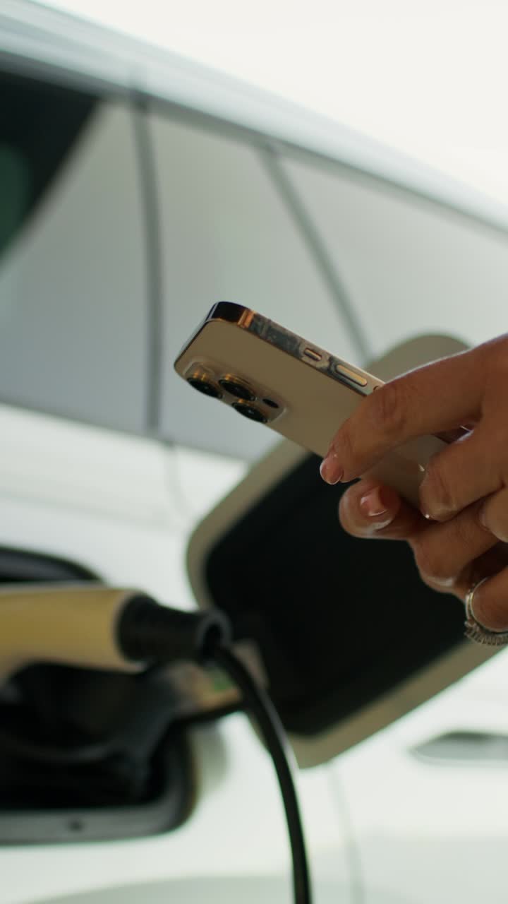mujer usando teléfono inteligente para administrar la carga de ev