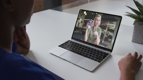 sección media de una mujer afroamericana haciendo una videollamada en una computadora portátil con una colega en la oficina