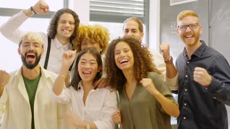 team of coworkers celebrating raising fist and looking at camera