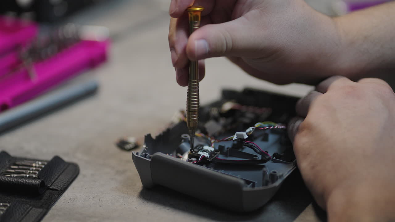 A close up of hands repairing a joystick with detailed screwdriver, precise and focused technical work