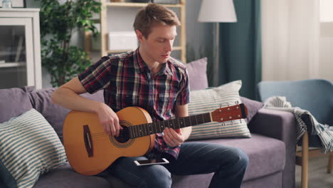 man playing acoustic guitar on a couch