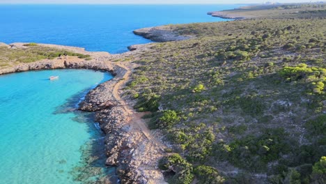 experience breathtaking aerial views of mallorca's coastline showcasing the beautiful cala varques area. lush greenery complements the stunning blue waters under clear skies.