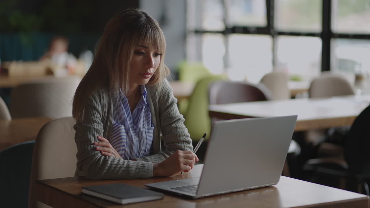 una mujer asiática se sienta pensativa y mira la pantalla de una computadora portátil. tormenta de ideas y ansiedad en su rostro. mujer asiática pensativa