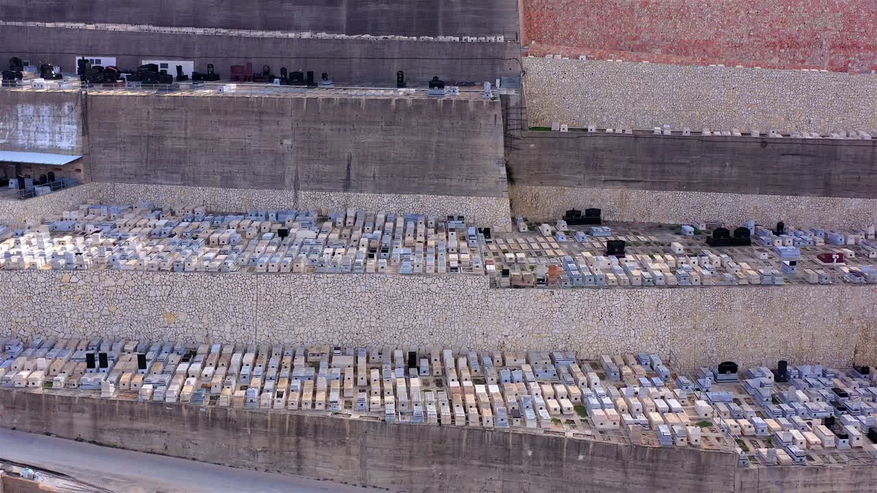 Aerial view of a large terraced cemetery with many graves