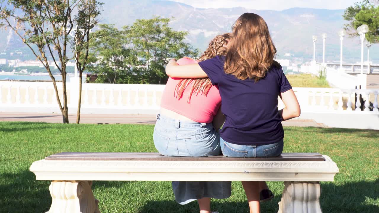 두 소녀가 공원에서 안고 앉아 있습니다.