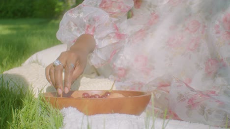 Beautiful-black-lady-on-picnic-in-free-time-eats-grapes-in-the-park,-in-shade