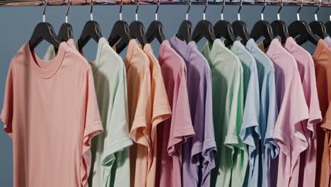 a row of pastel-colored t-shirts on hangers, captured from a side angle
