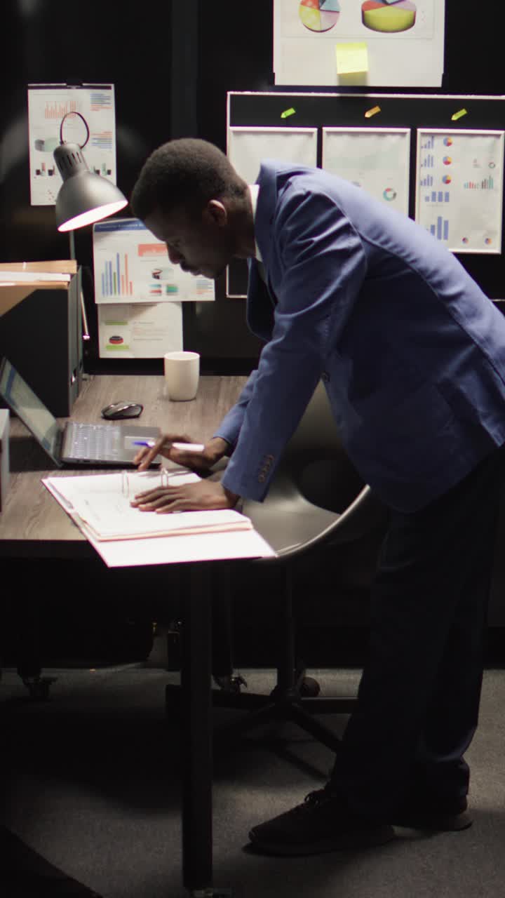 Man Working at Desk in Office with Charts and Documents