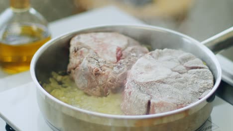 woman putting raw beef in frying pan on electric stove