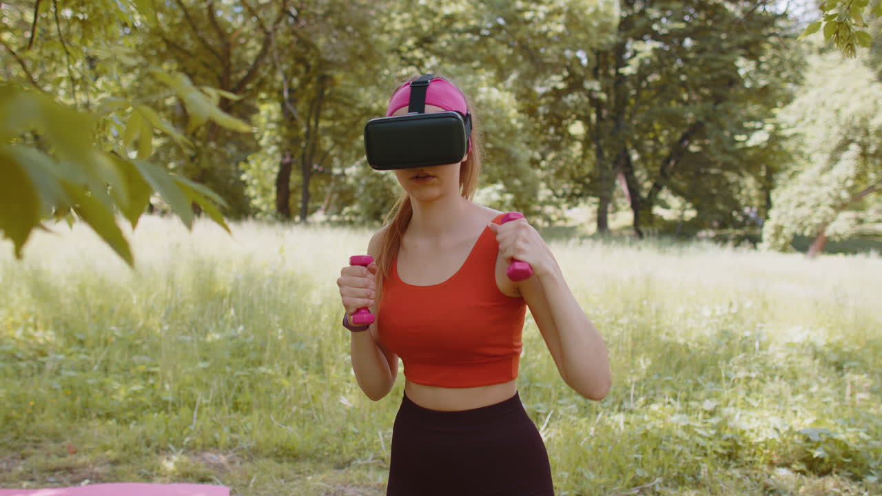 chica atlética en casco de auriculares vr haciendo ejercicios de fitness ejercicios de boxeo con pesas en el parque