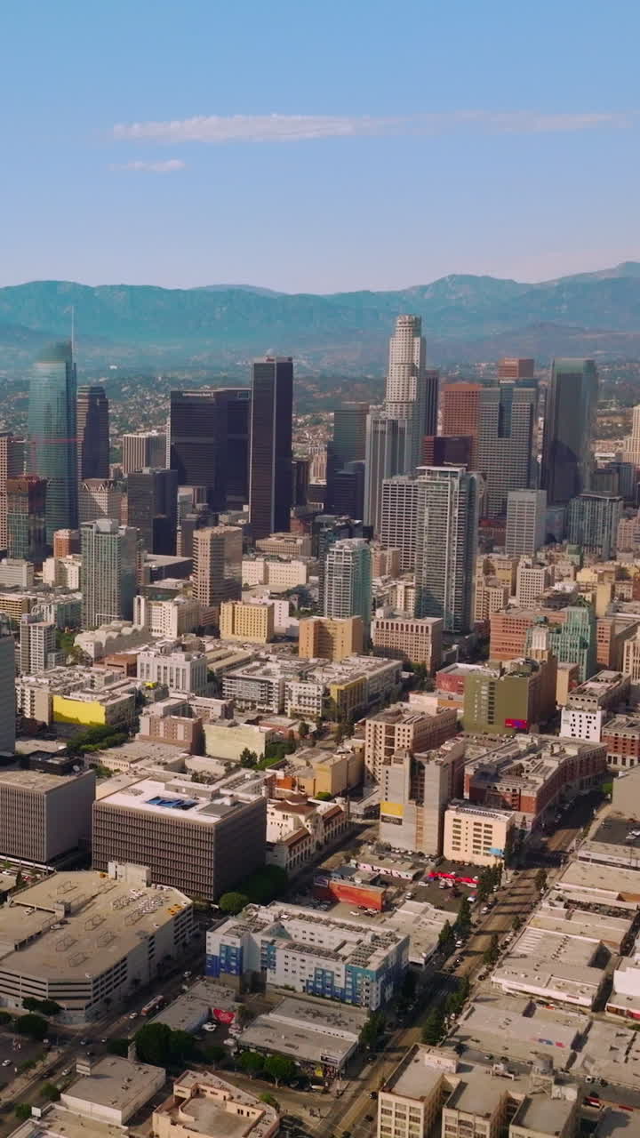 Beautiful skyscrapers of downtown financial centre of Los Angeles, California. Sunny urban scenery stretching up to hazy hills. Blue skies at backdrop. Vertical video