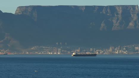 Vista-Panorámica-De-La-Montaña-De-La-Mesa-Con-Un-Buque-De-Carga-En-Primer-Plano-Al-Atardecer-En-Sudáfrica