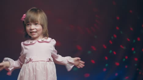 cute little girl in vintage pink dress is spinning in dance and rejoicing