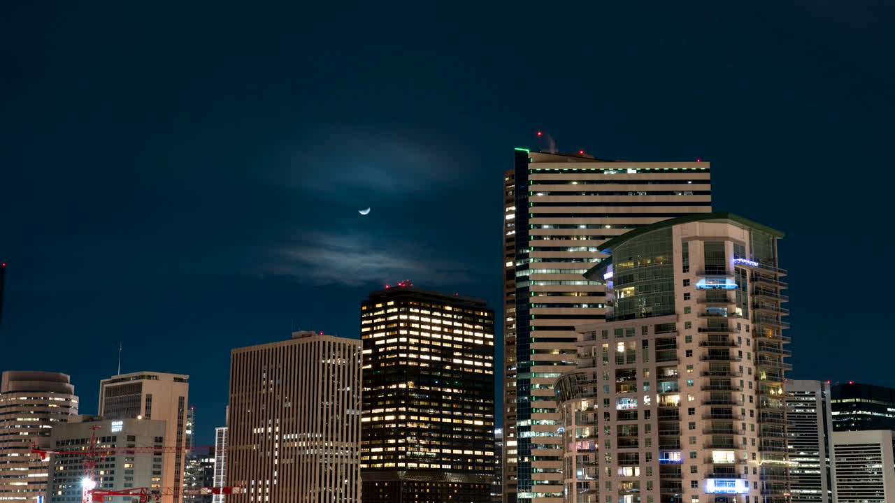 zoom motion timelapse de la puesta de luna sobre los rascacielos iluminados en el horizonte de denver