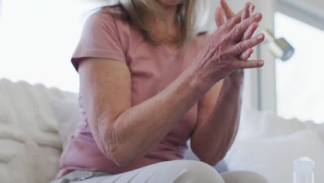sección media de una mujer mayor desinfectando sus manos en casa