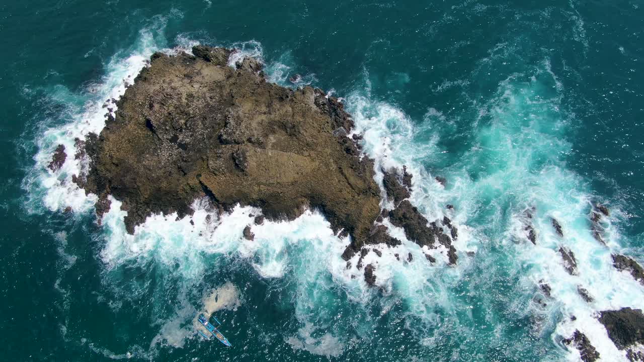 Barca tradizionale vicino a un'isola corallina bagnata dalle onde dell'oceano sulla costa di Menganti, Giava.