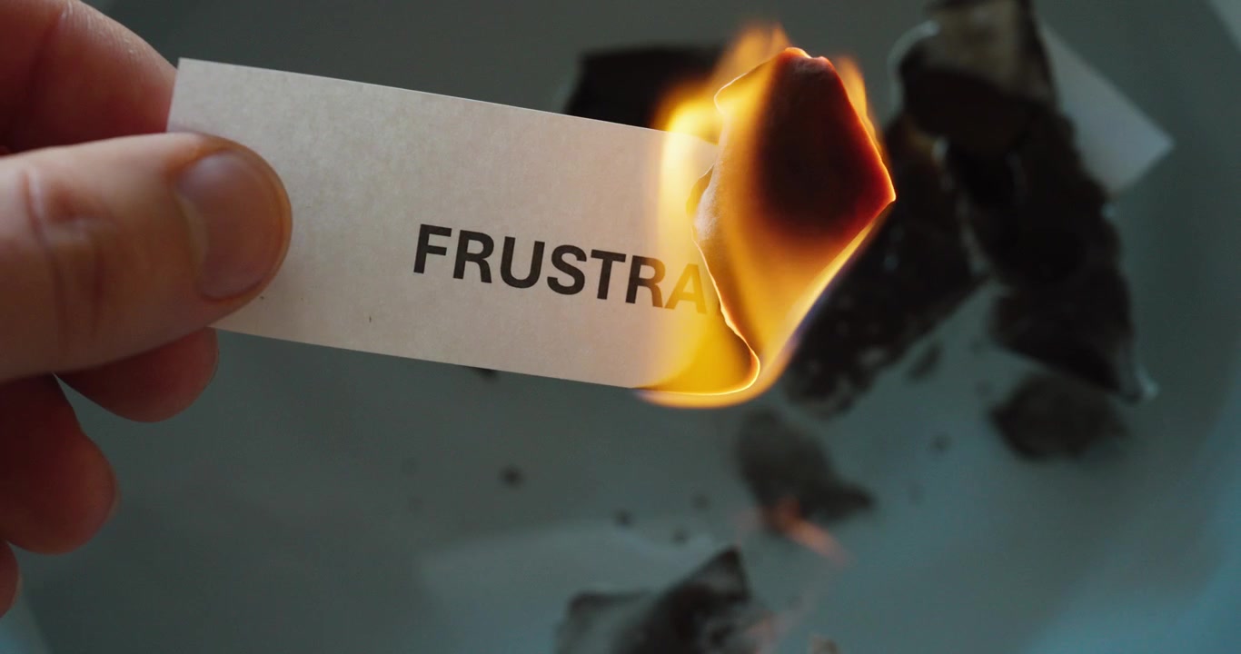 Nærbillede af papir mærket "frustration", der brænder, symboliserer følelsesmæssig frigørelse, stresslindring og at give slip på negative følelser.