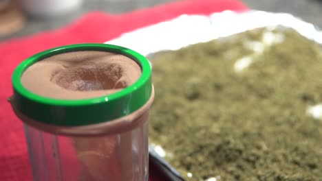 view of mans hand putting leaves of marijuana in the jar