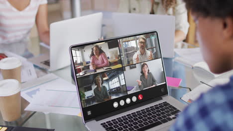 african american man using laptop for video call, with diverse business colleagues on screen