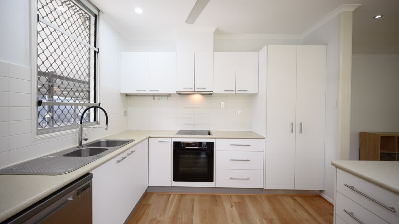 Stainless Steel Appliances and Electric Stovetop in Beige White Kitchen with Silver Accents