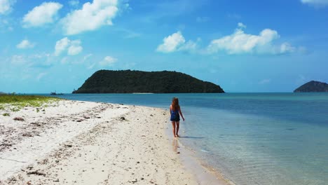 Caucasian-young-attractive-girl-leisurely-walks-through-the-calm-waters-on-the-sandy-coast