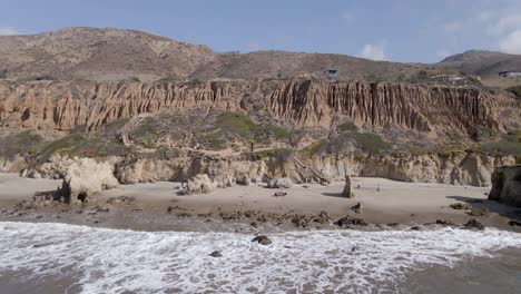 Vista-Escénica-De-Acantilados,-Montañas-Y-Olas-Del-Océano-Que-Se-Lavan-En-La-Orilla-En-La-Playa-El-Matador,-Malibu,-California,-Estados-Unidos---Retroceso-Aéreo