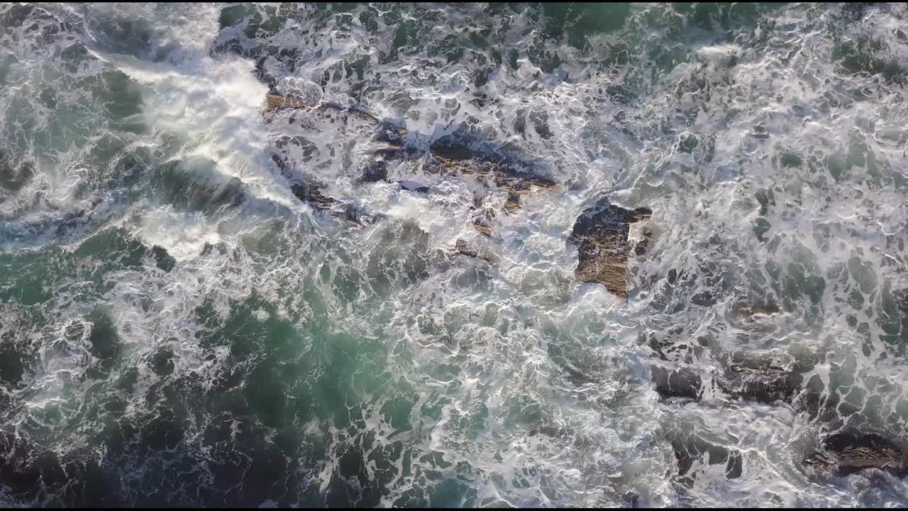 Aerial view to ocean waves with the waves crashing on the rocks