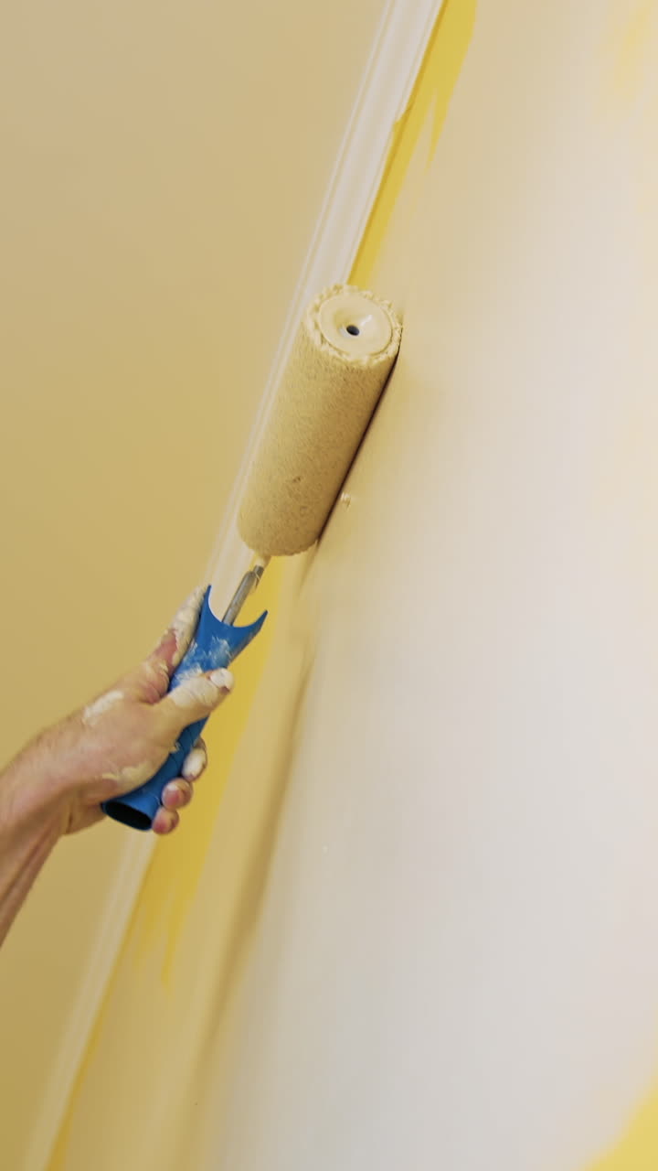 Man painting wall in room. Close up of man in new apartment renovating room painting wall with brush roller
