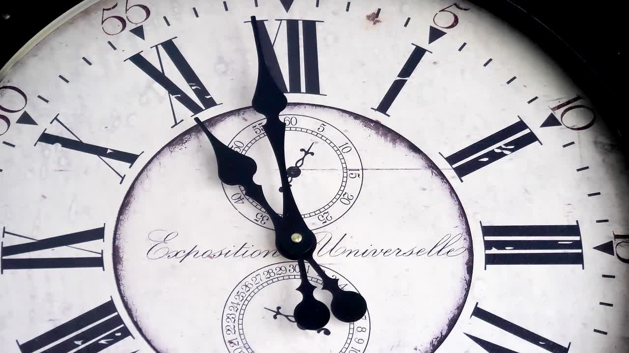 The old white and black wall clock with the ticking hands