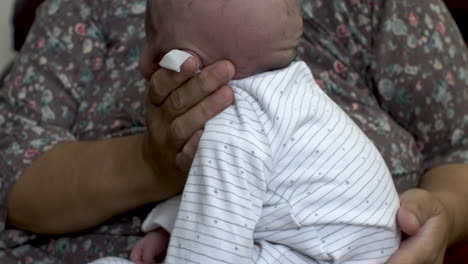 mother holding head of newborn baby and rubbing his back for burping